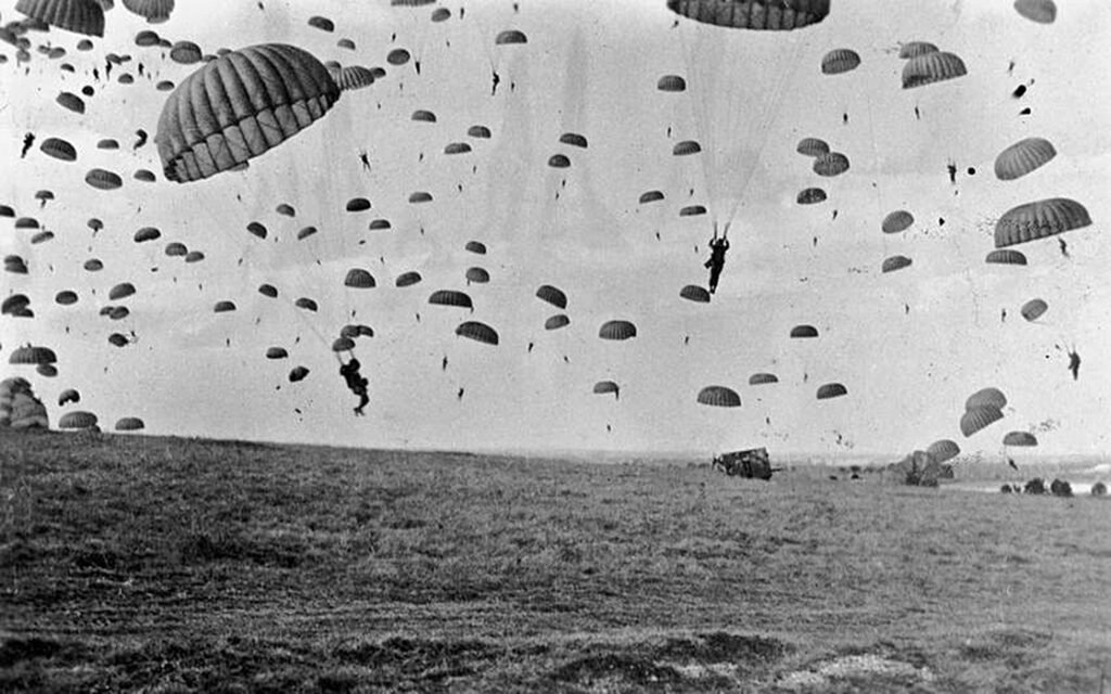 Paraquedistas aliados saltando sobre a Holanda durante a Operação Market Garden em 17 de setembro de 1944, com aeronaves C-47 ao fundo.