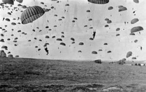 Paraquedistas aliados saltando sobre a Holanda durante a Operação Market Garden em 17 de setembro de 1944, com aeronaves C-47 ao fundo.